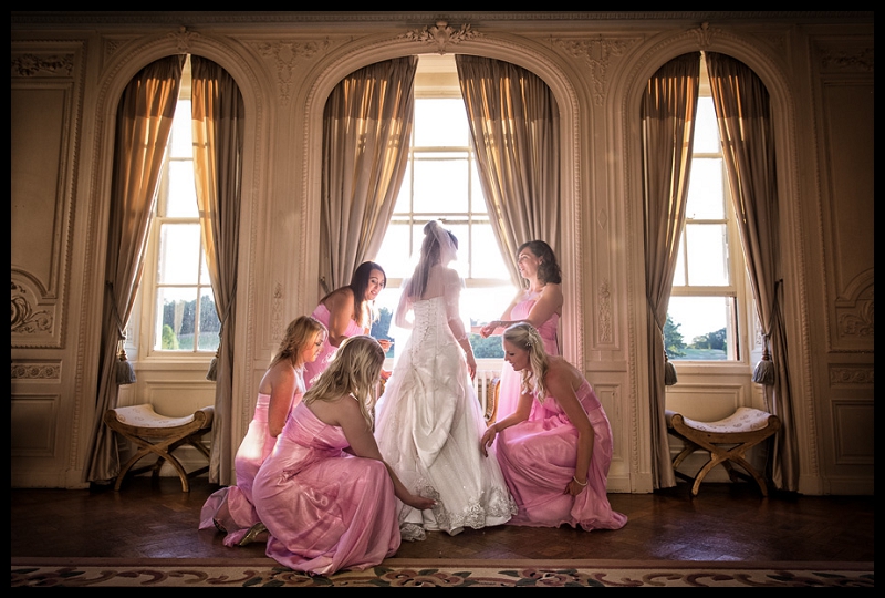 Beautiful photo of bridesmaids adjusting bride's dress at Addington Palace by Peter Denness.jpg