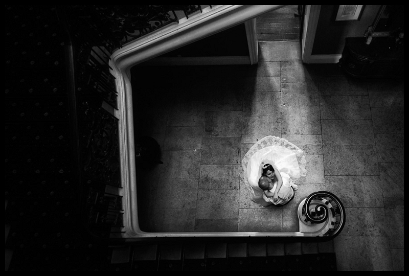Timeless, romantic black and white image of bride and groom kissing, taken from above on stairs at Addington Palace.jpg