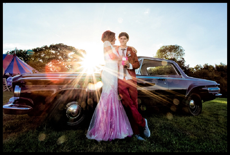 Vintage carnival themed wedding photo of dodge wedding car with bride and groom