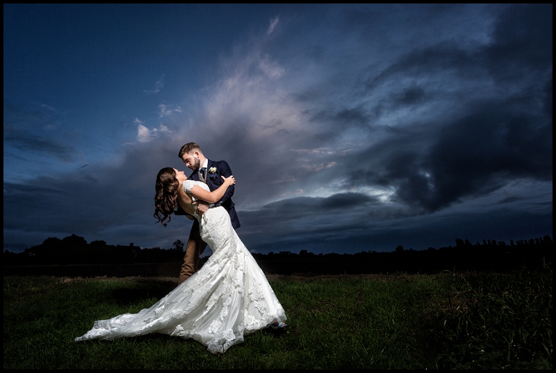 Beautiful portrait of groom dipping bride at the Granary Estates with dramatic sky
