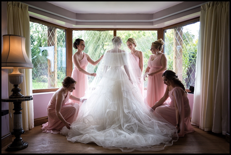 bridesmaids adjusting brides dress